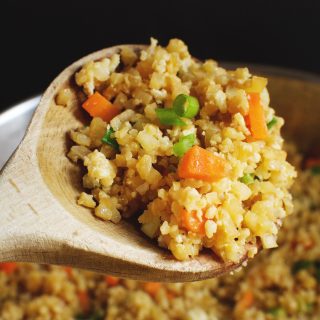 Easy Low-Carb Cauliflower Fried Rice Recipe in a wooden spoon.