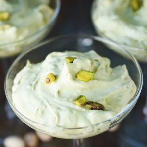 Low-Carb Pistachio Mousse Recipe served in a champagne glass with pistachios in the background.