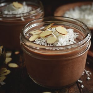 Chocolate Almond Avocado Pudding-in a jar with almonds and coconut sprinkled on top.