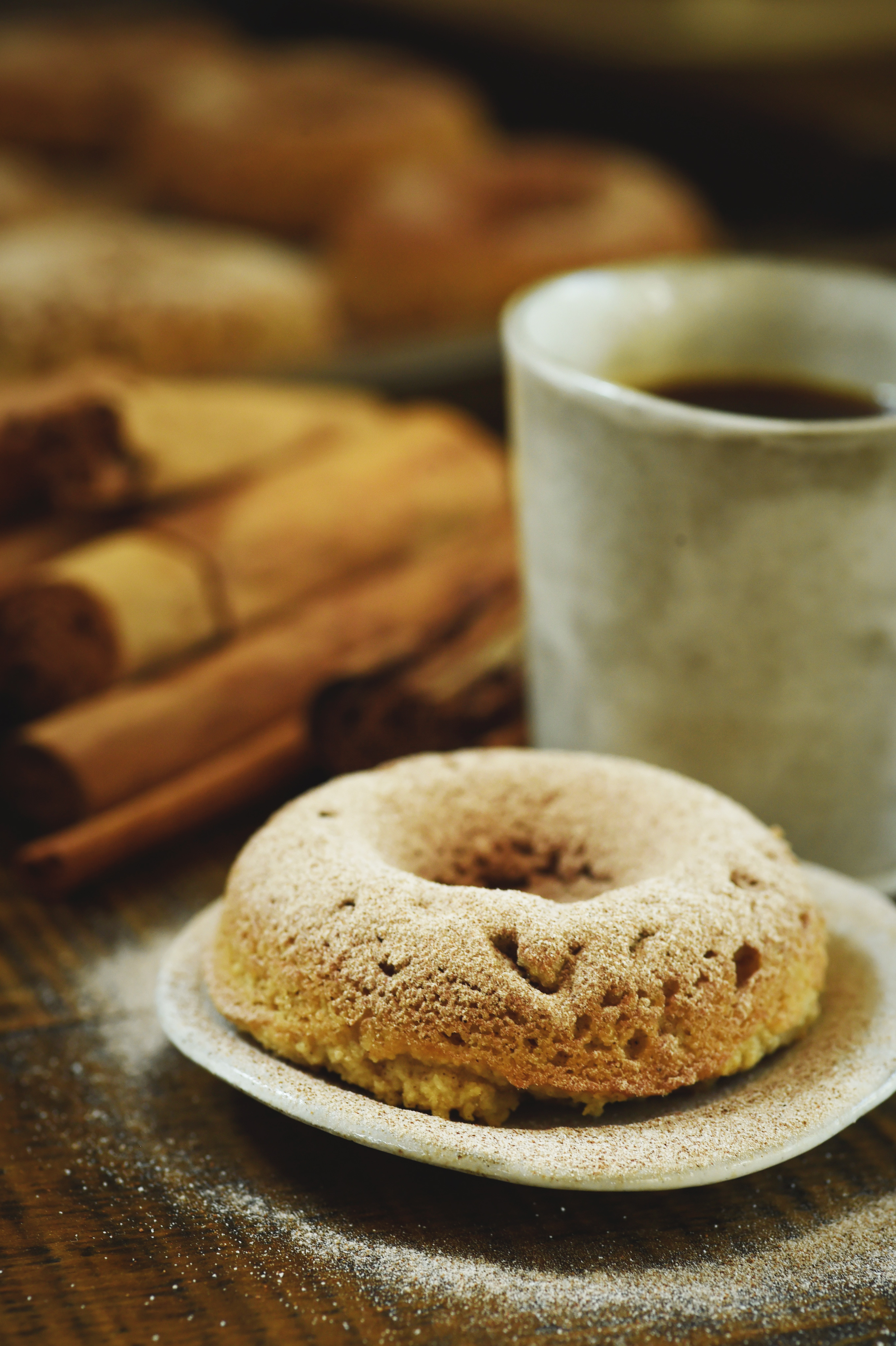 Low-Carb Cinnamon Sour Cream Donuts-shown with coffee and cinnamon sticks.