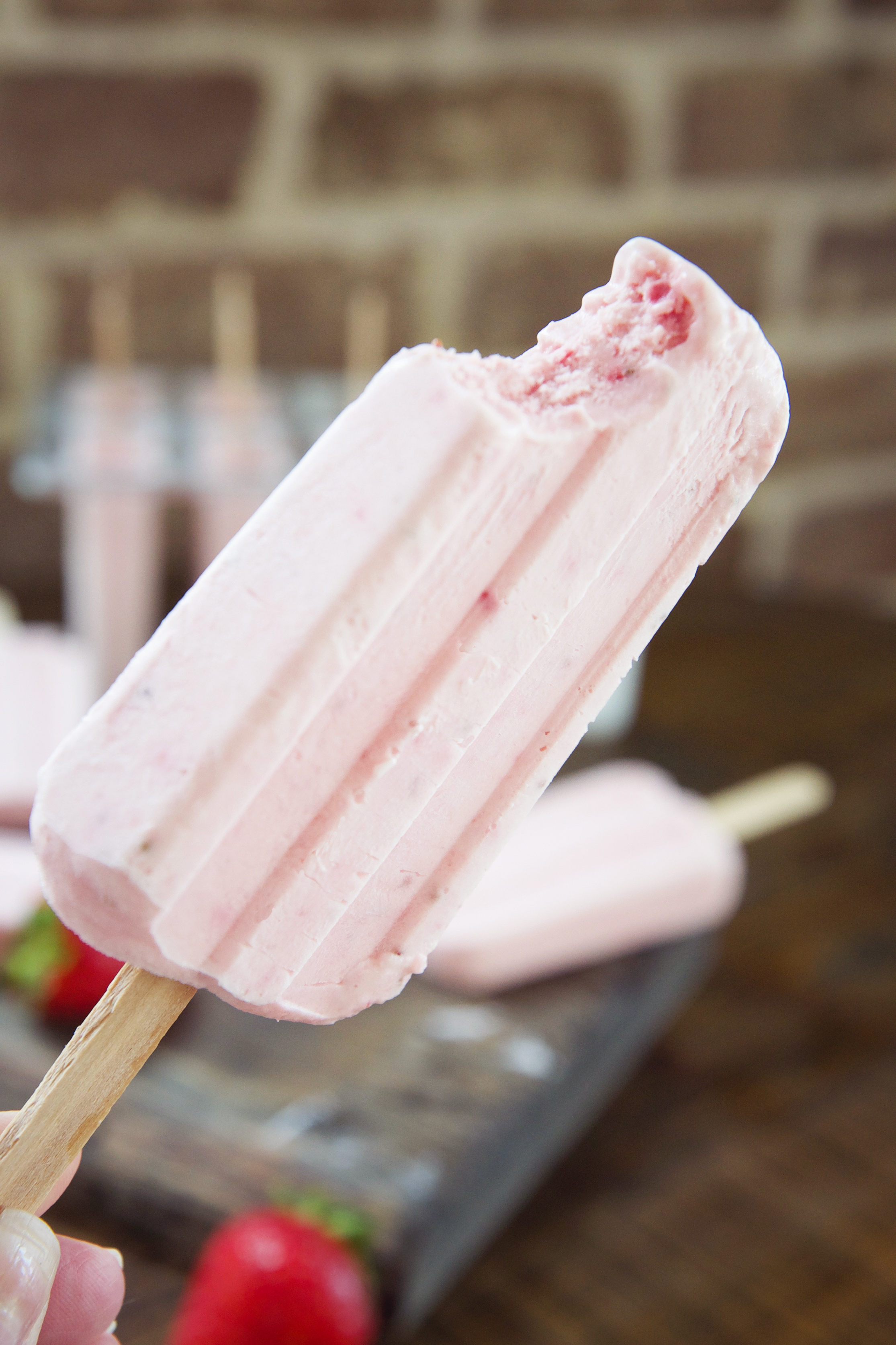 Low-Carb Strawberry Cream Popsicles- one popsicle with bite taken out