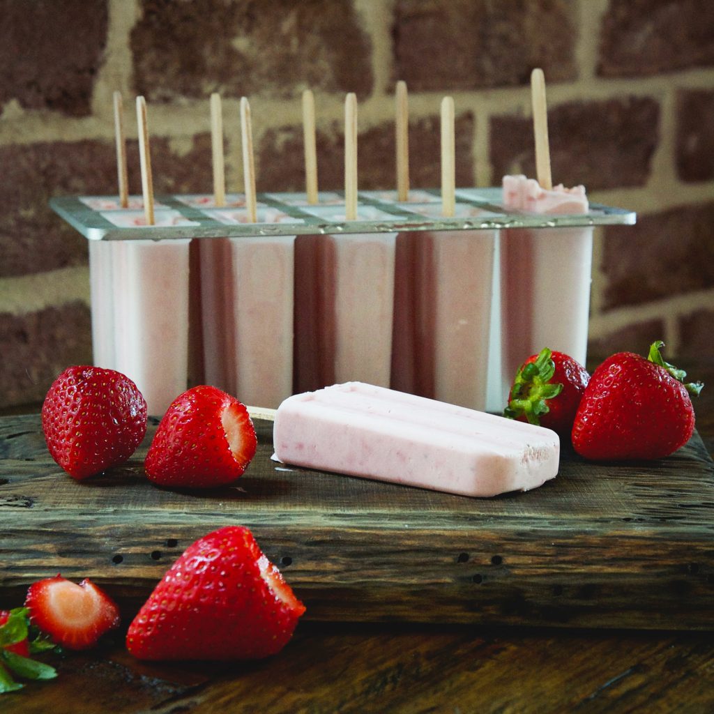 Low-Carb Strawberry Cream Popsicles-One out of the mold with others still in the mold.