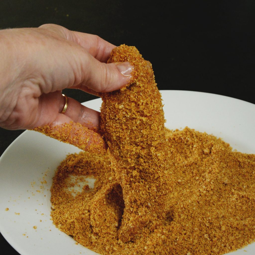 Low-Carb Buffalo Chicken Tenders-dipping in the cheese mixture