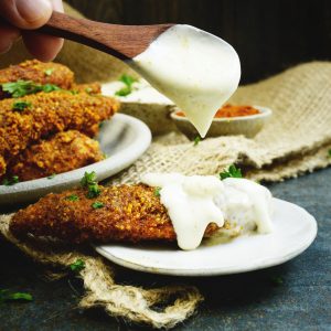 Low-Carb Buffalo Chicken Tenders-Spooning blue cheese dressing over.