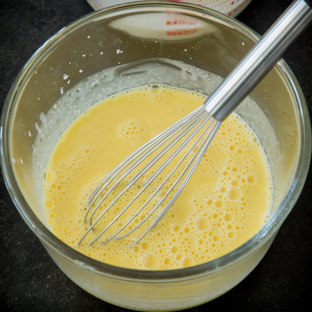 Whisking cream into beaten egg yolks.