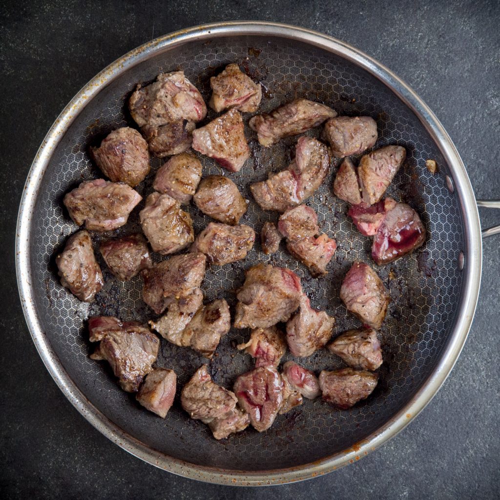 Browning the meat in a pan.