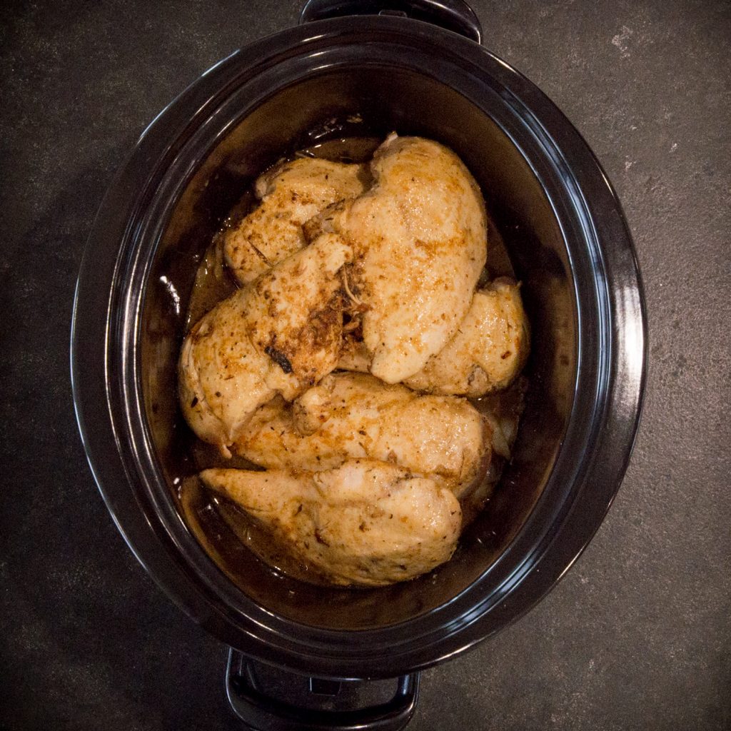 Adding chicken to the crockpot.