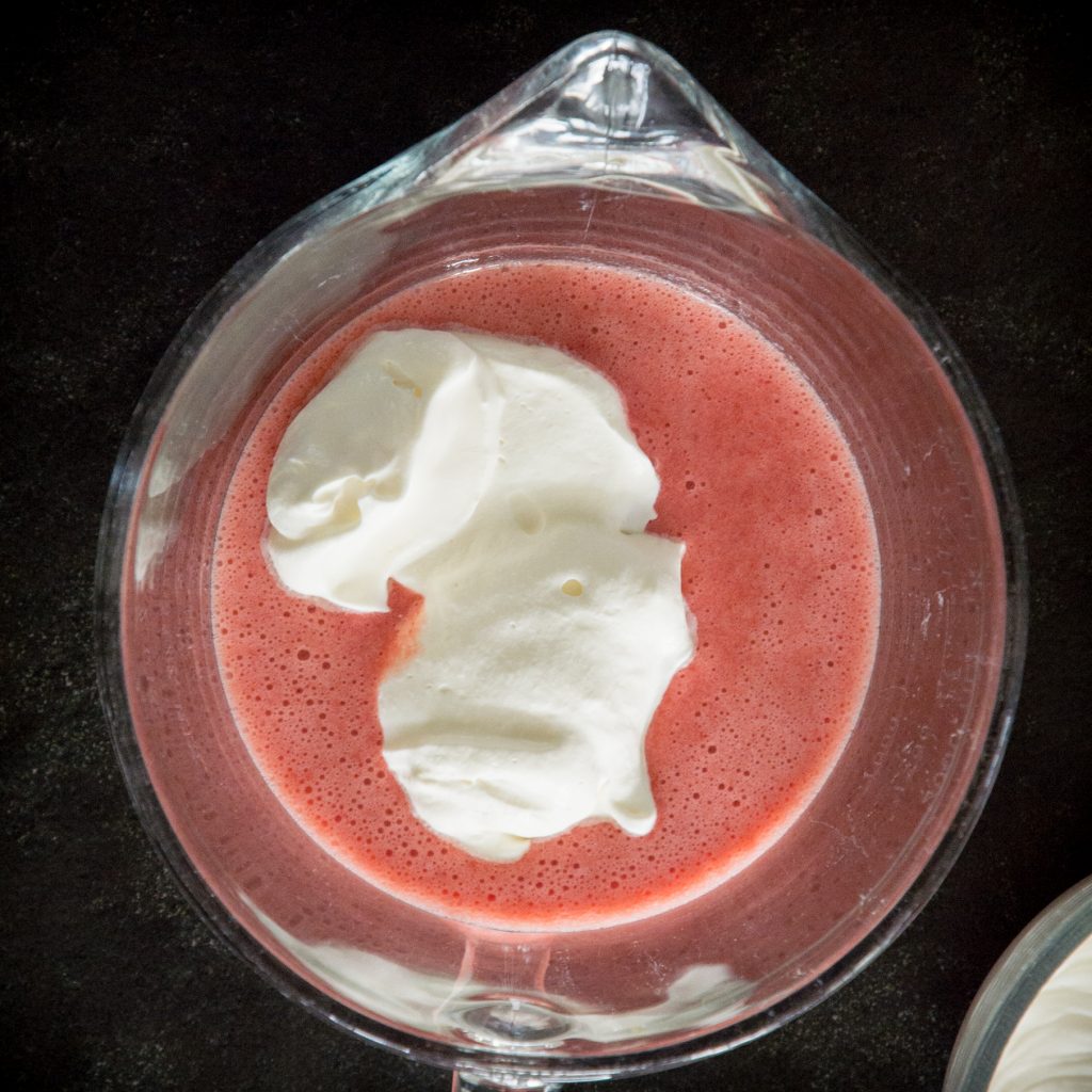 Adding 1/3 of whipped cream into strawberry gelatin.