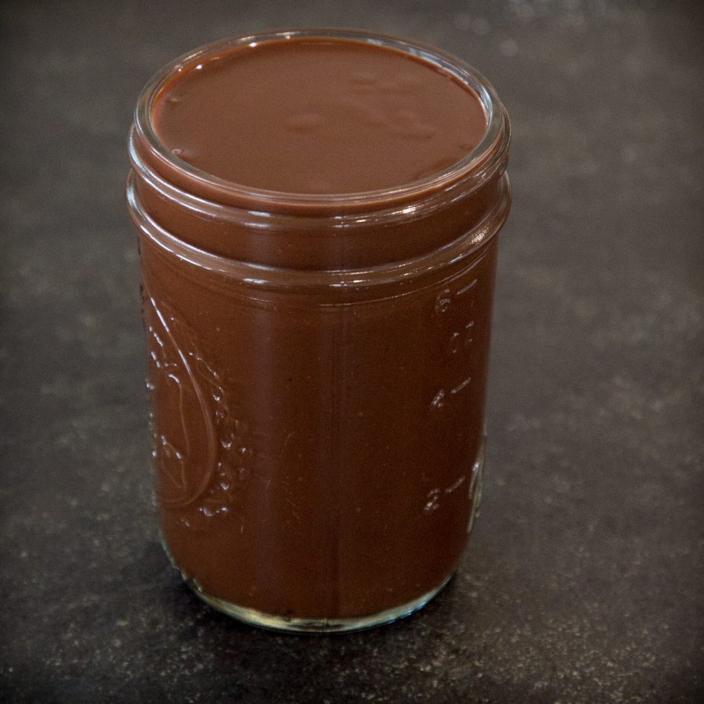 Low-carb hot chocolate sauce poured into glass jar.
