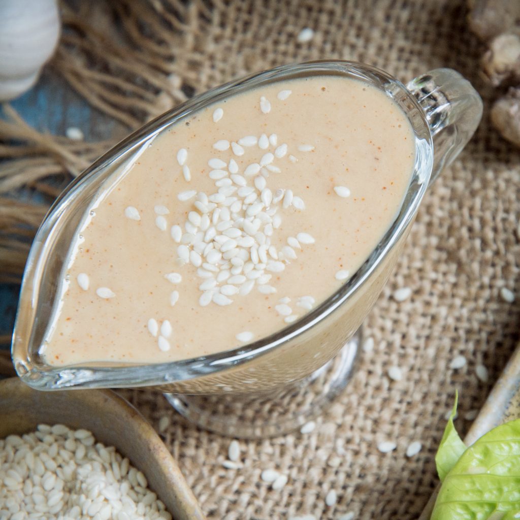 Top view of low-carb sesame ginger salad dressing on a glass gravy boat.
