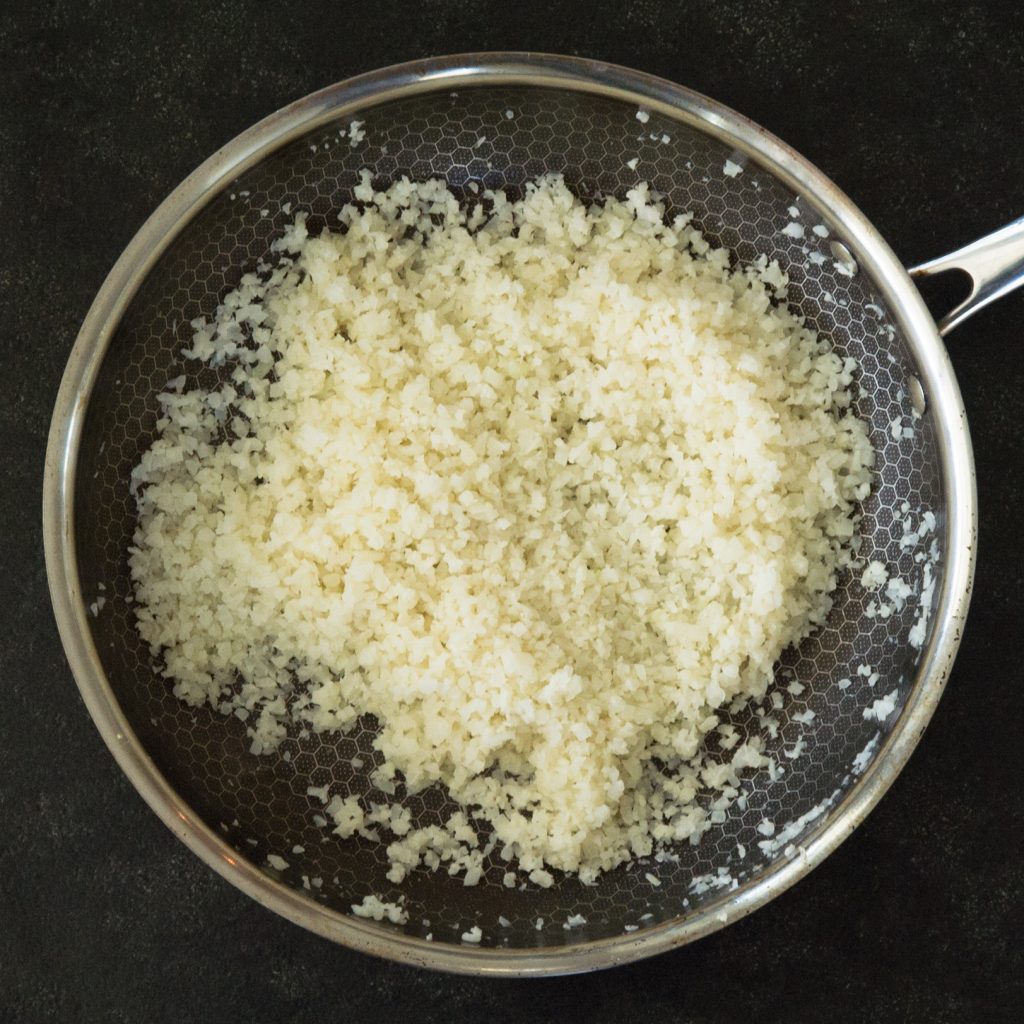 Overhead photo of grated cauliflower on a pan.