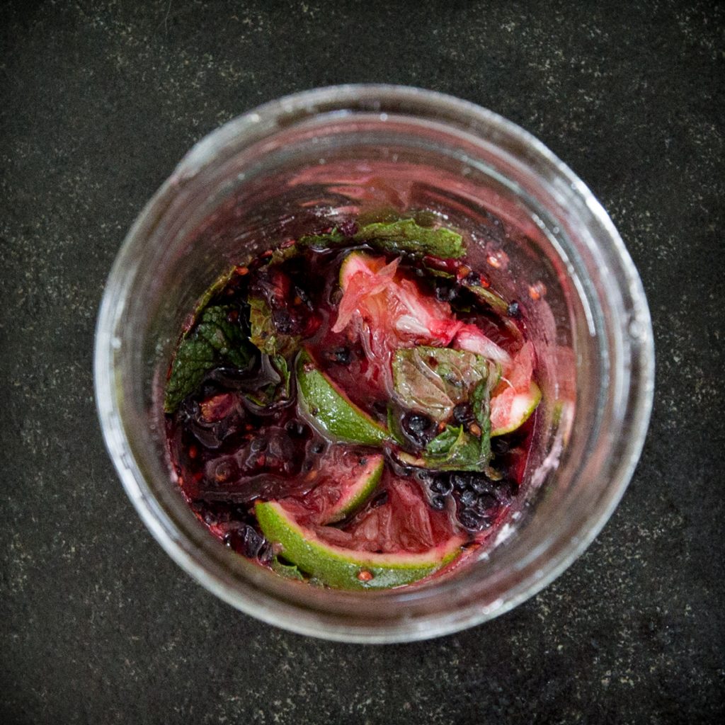 Overhead process photo of low-carb blackberry mojito ingredients in a glass.