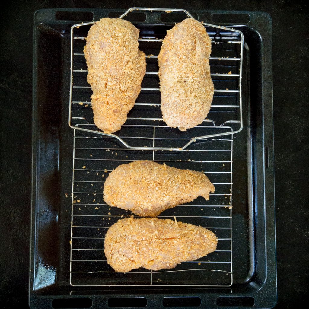 Process photo of the breaded chicken on the pan before baking.