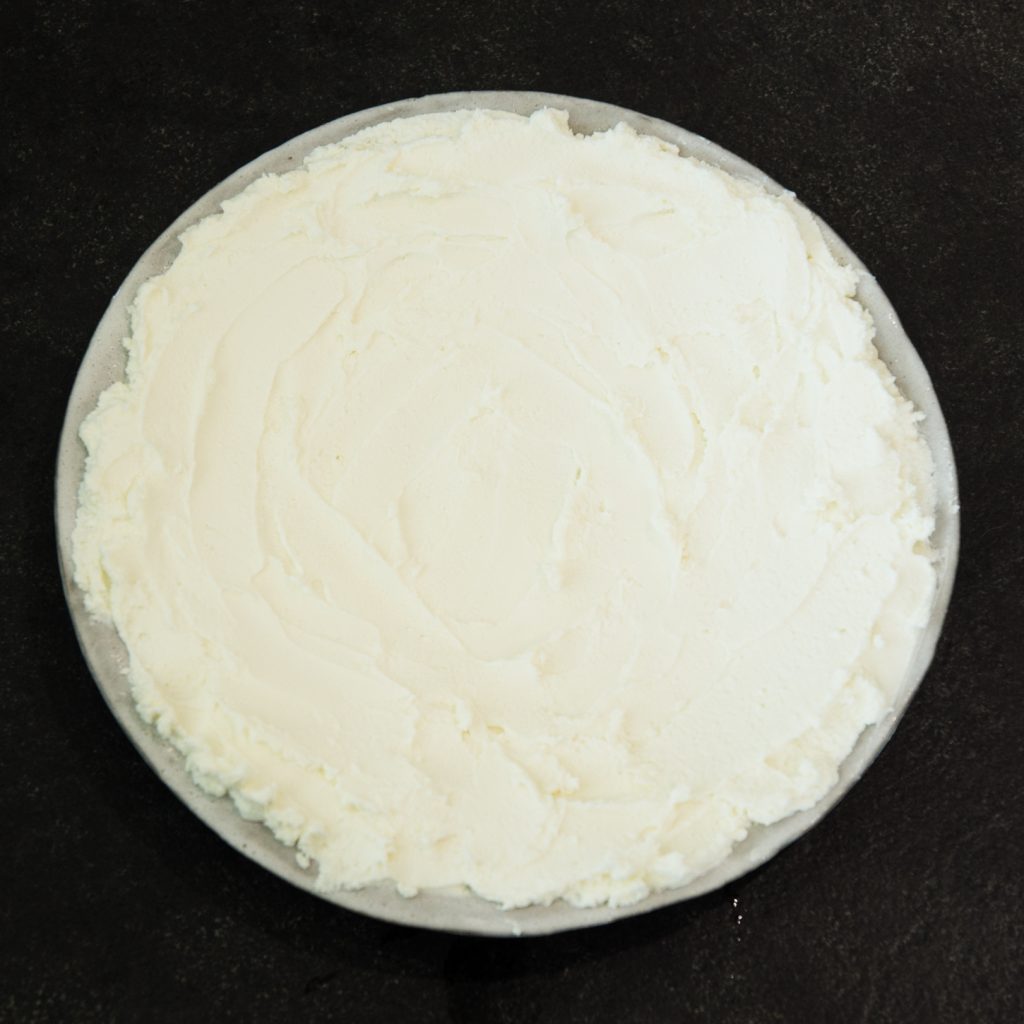 Process photo of goat cheese spread on plate.