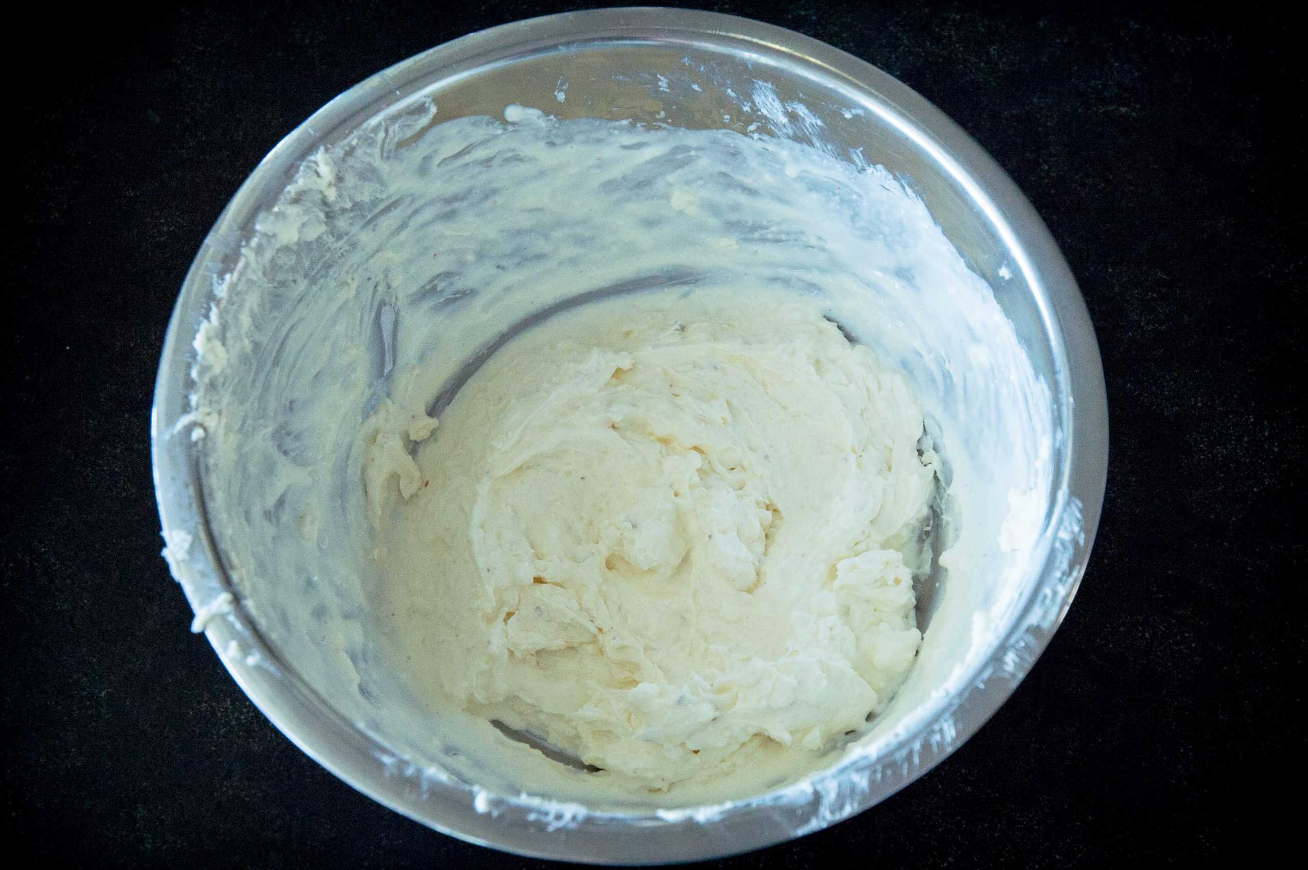 Process photo of thick cream cheese mixture in a bowl.