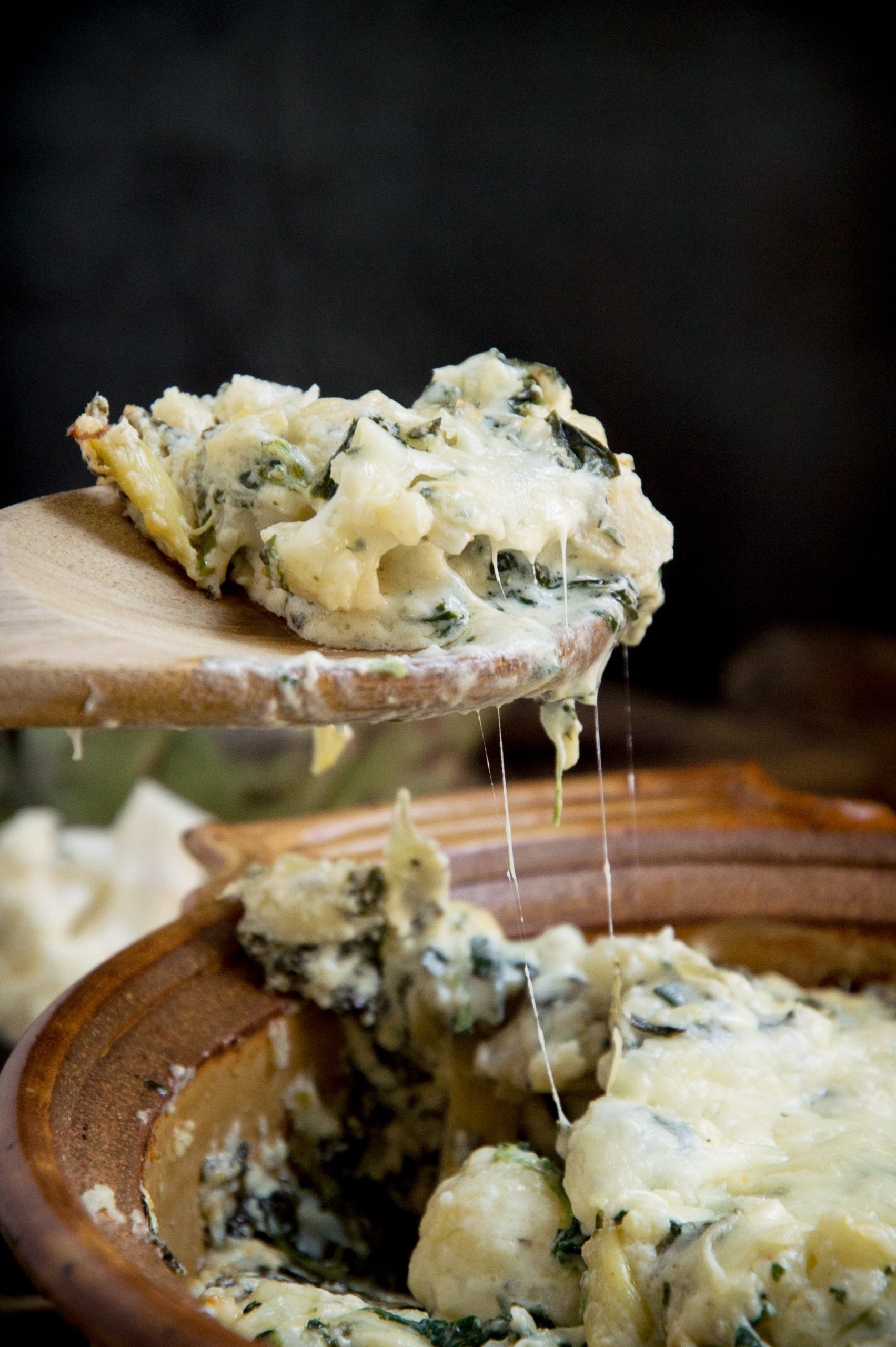Spoonful of Keto Spinach Artichoke Casserole with stretchy cheese.