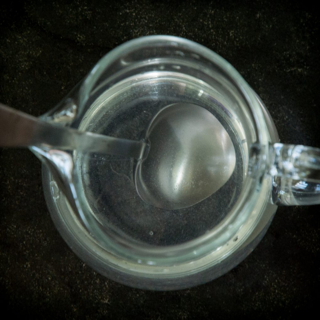 Process photo of water and sweetener combined in a glass pitcher.