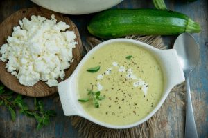 Keto Zucchini soup in a bowl with feta cheese on a plate