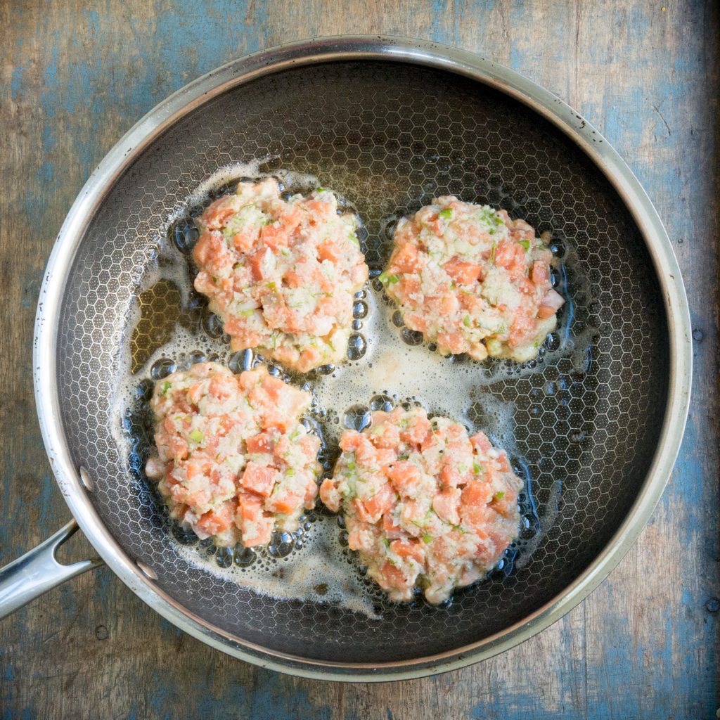 Adding the salmon cakes to the hot skillet.