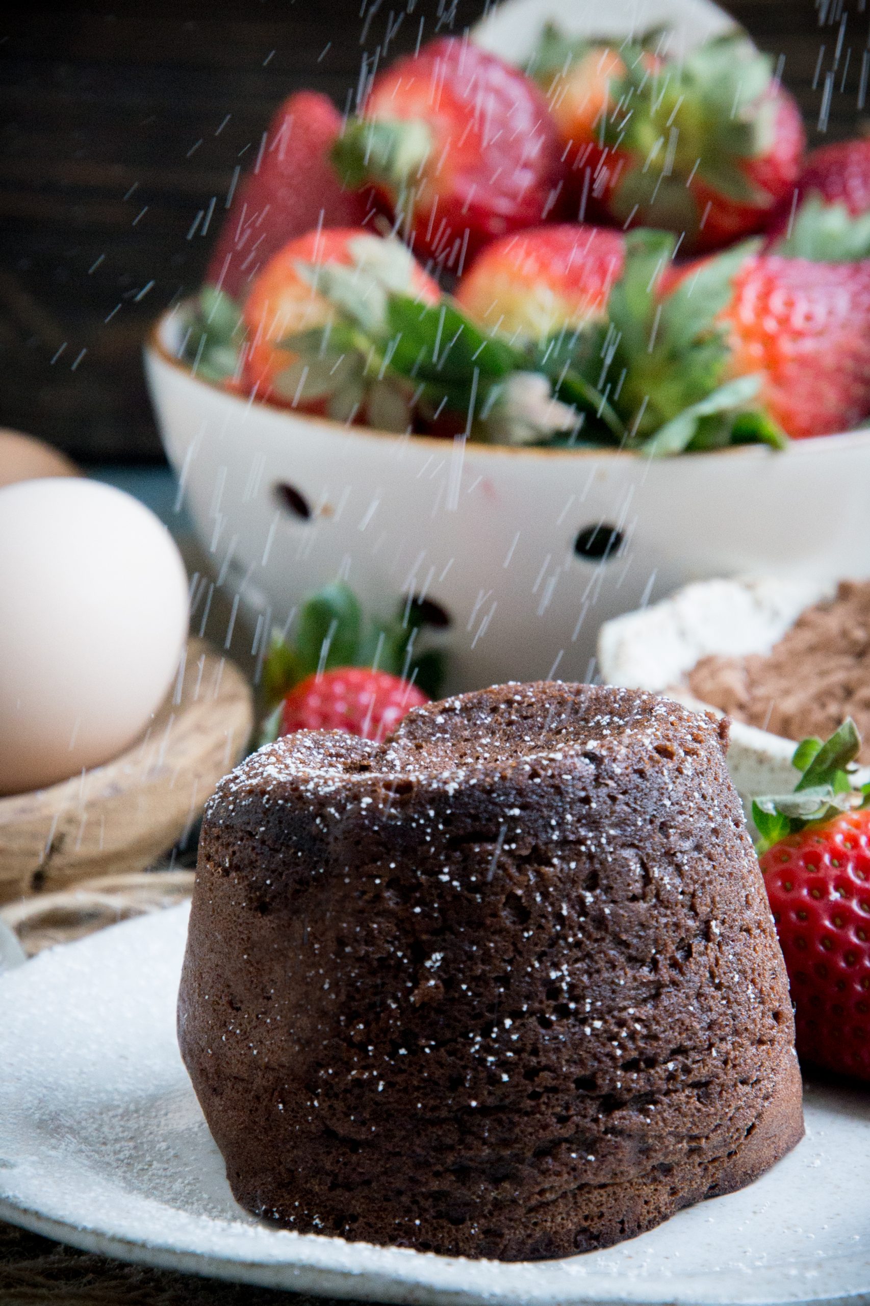 Sprinkling powdered sweetener over a keto chocolate lava cake.
