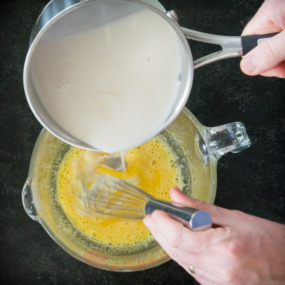 Adding the coconut milk to the egg yolk mixture.