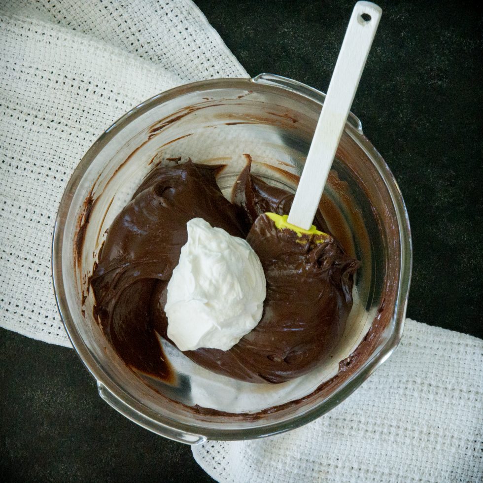 Adding one third of the whipped cream to the chocolate mixture.