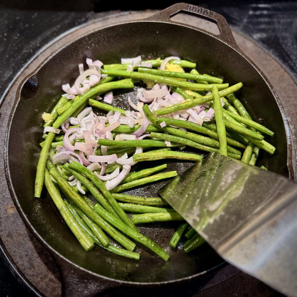 French Green beans, shallots, and garlic sautéing in cast iron pan