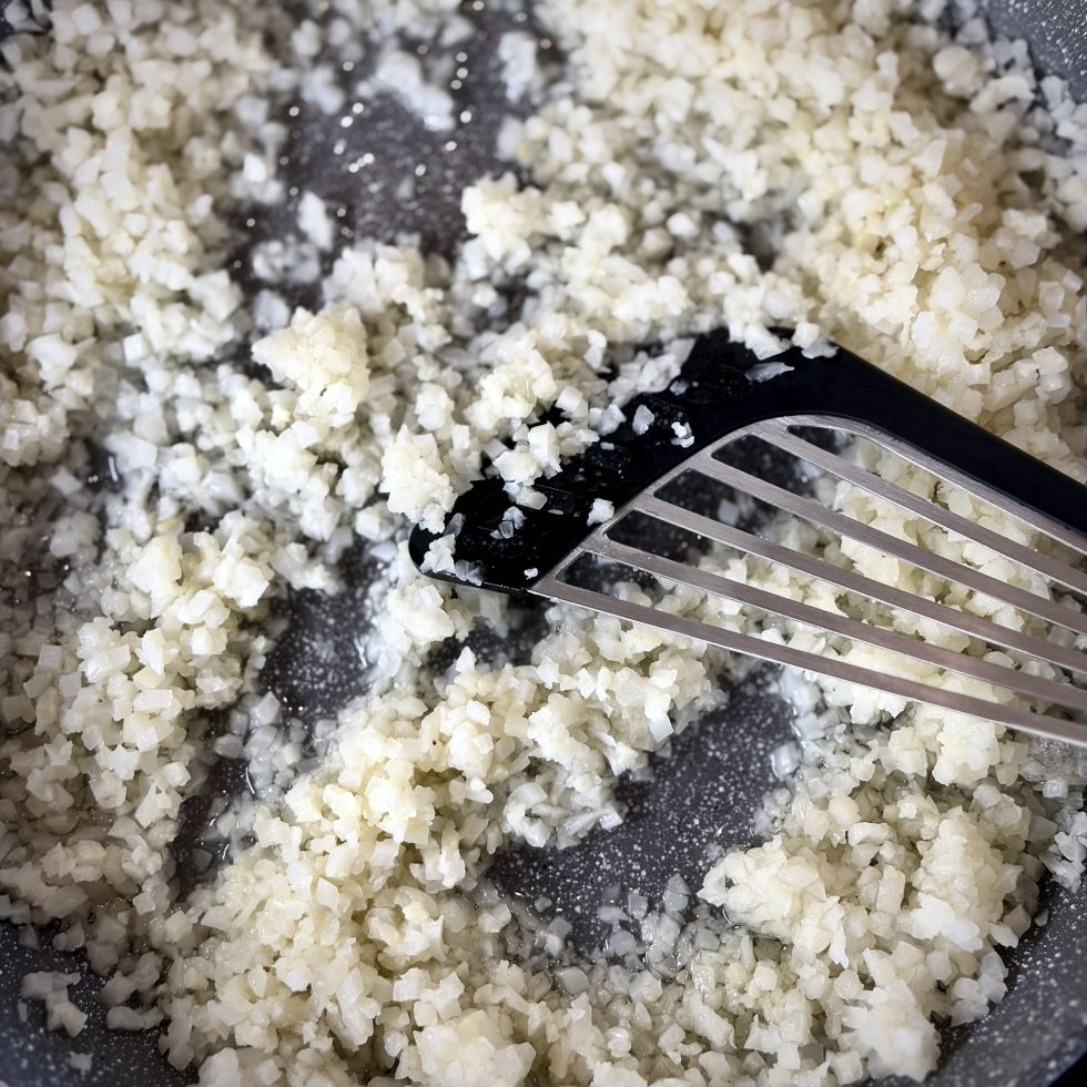 Cauliflower rice being stirred in a sauce pan
