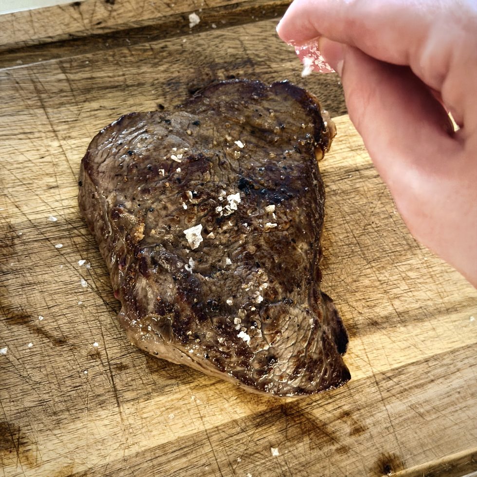 sprinkling flaky salt onto cooked steak
