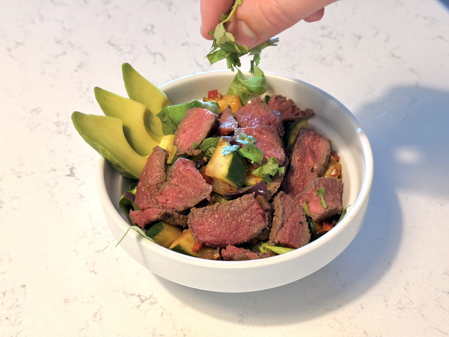 sprinkling parsley over finished burrito bowl