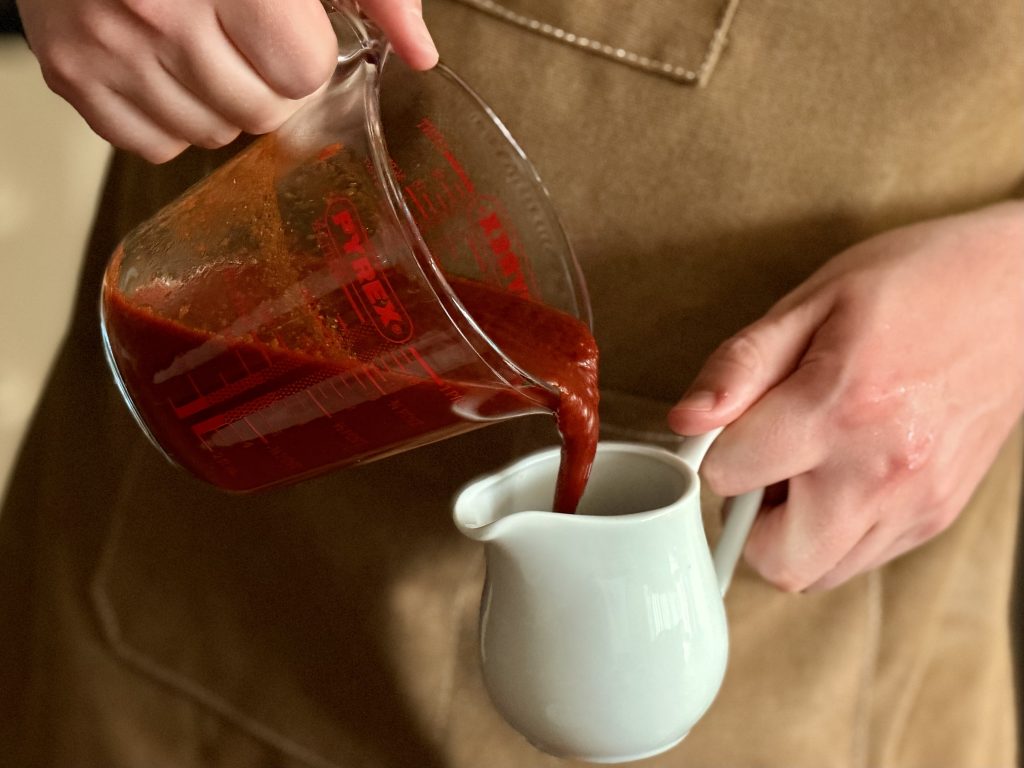 keto bbq sauce being poured into a serving pitcher