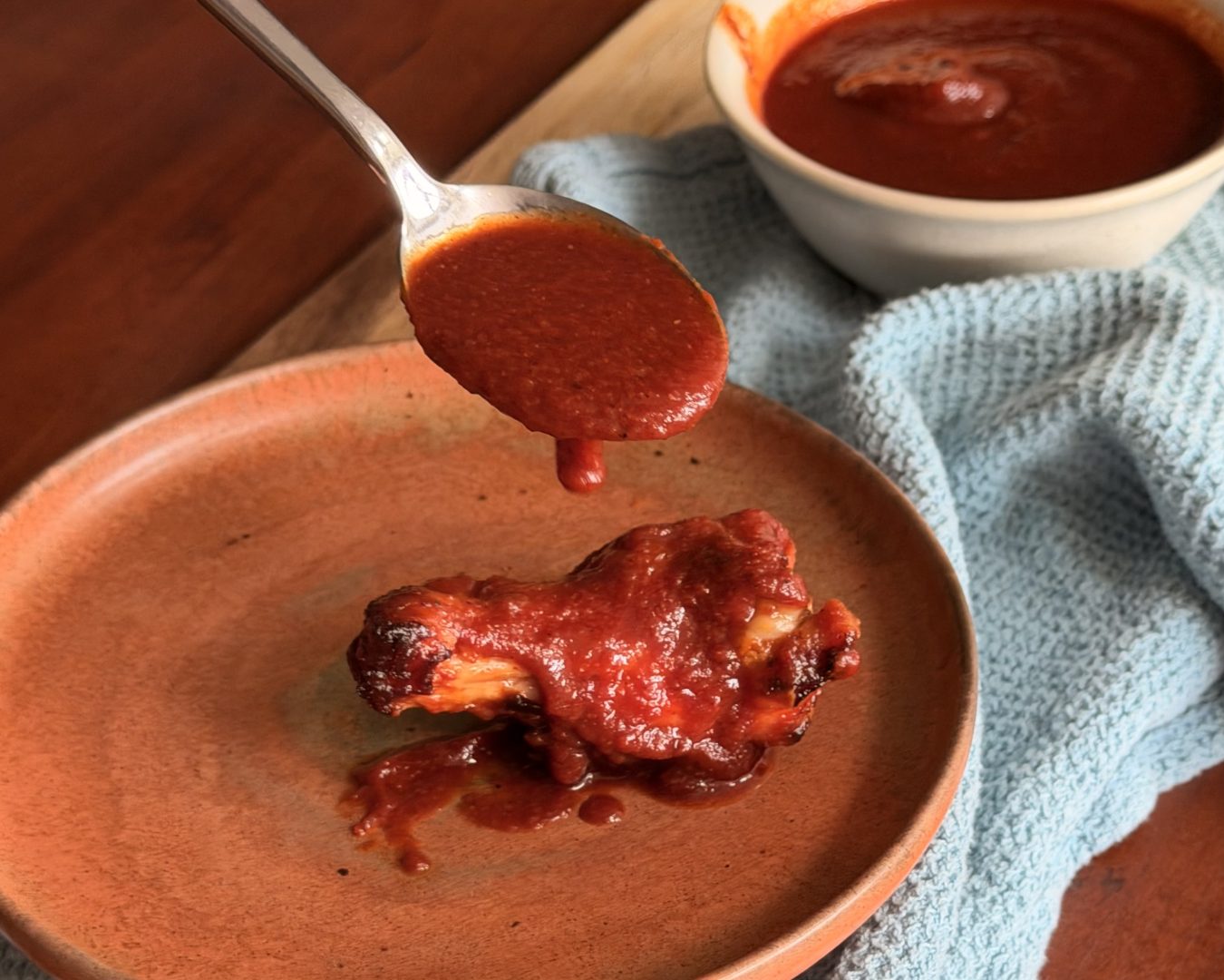 Keto BBQ sauce being spooned onto a chicken wing